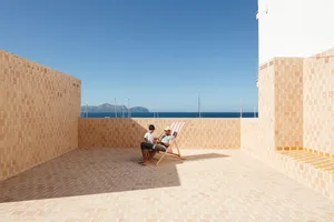 A patio with a tiled floor, a lounge chair, and a table.