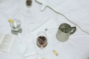 A bedroom scene featuring white textiles, wine glasses, and ice-filled pitcher.