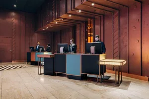 A modern industrial hotel lobby features polished metal and wooden surfaces.