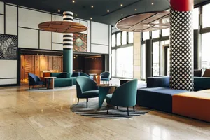 Modern office space featuring concrete columns, leather chairs, metal accents, and glass partitions.
