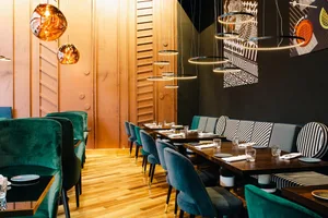 Modern restaurant interior with velvet seating and wood accents, featuring contemporary lighting fixtures and a stylish patte