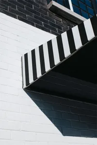 A modern exterior building facade with a striped awning and brick wall.