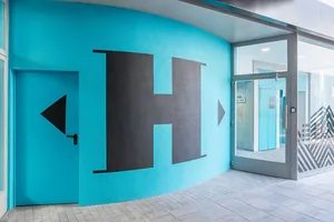 Blue painted exterior wall featuring a bold graphic design.