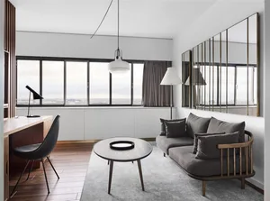 A minimalist living room with a grey sofa, wooden coffee table, and a large window.