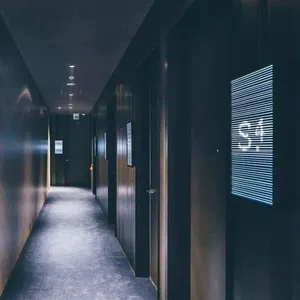 Dark wooden hotel corridor with a digital display panel showing the number 34.