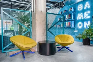 A modern, industrial-style lobby with concrete flooring, metal furnishings, and leather chairs.