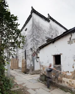 A narrow, urban street with ancient buildings made of concrete and wood.