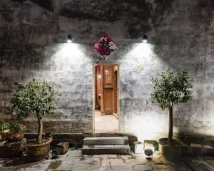 Concrete entrance with illuminated sign and plants.