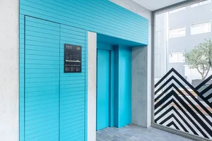 Blue-painted elevator doors with concrete columns in a hotel lobby