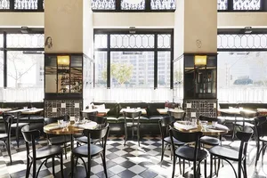 A cafe interior with tables and chairs arranged on a checkerboard-patterned floor.