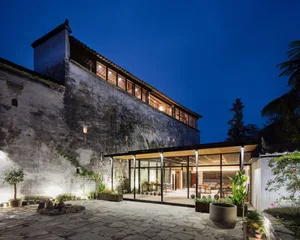 A night view of a concrete accommodation building with a glass entrance and illuminated interior.