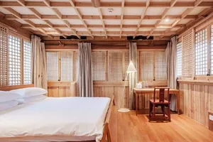 Spacious bedroom with wooden furniture and lattice windows, featuring white bedding and a desk.