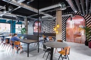A spacious, modern coffee shop with industrial design elements, concrete flooring, and exposed pipes.