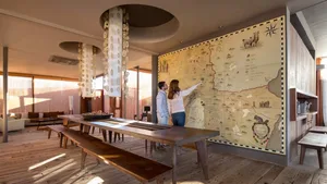 Two people studying an intricate wall map in a warm, industrial-style restaurant interior