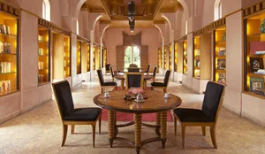 A library interior with warm wood furniture and shelves filled with books and decorative items.