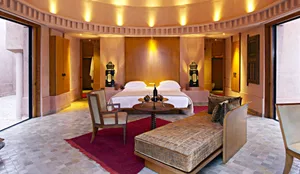 A luxurious bedroom interior with wooden furniture, a red rug, and warm lighting.