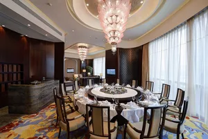 A luxurious dining room with marble tables, glass chandeliers, and wooden chairs.