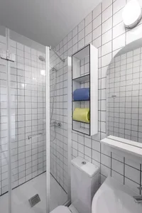 A minimalist bathroom featuring white square tiles with black grout lines.