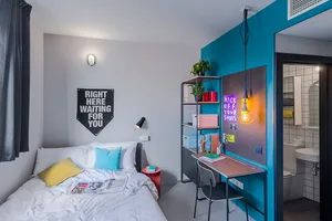 A minimalist bedroom with urban art accents, featuring a neatly made bed with white bedding and colorful throw pillows.