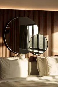 A minimalist bedroom with two circular mirrors mounted on a wooden wall, creating a modern and sleek atmosphere.
