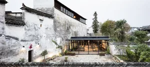 Modern minimalist building exterior and interior with concrete walls, glass doors, and greenery.