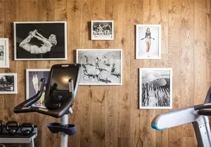 A minimalistic workout area featuring wood paneling, exercise equipment, and framed workout photos on the wall.