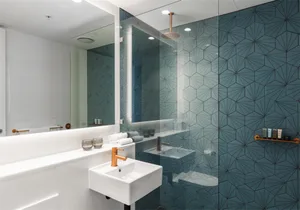 Modern bathroom with blue patterned tiles on the walls and a white sink.