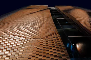 A modern building facade made of a repeating pattern of bricks.
