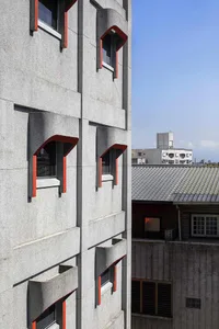 A modern, concrete exterior of a building with red accents.