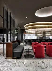 Modern coffee shop interior featuring marble floors, metallic railings, and red velvet seating.