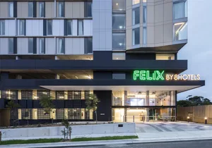 Modern hotel exterior with metal accents, glass windows, and concrete facade.