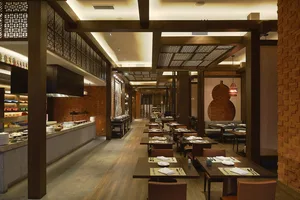 Modern kitchen area with brick walls and wooden floors, featuring a long dining table, chairs, and a variety of dining setups