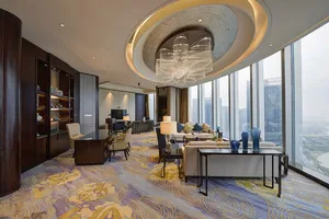 Modern lounge with glass view featuring contemporary furniture and large windows with a cityscape backdrop.