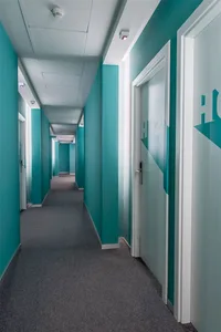 A modern office corridor with blue painted walls and white doors.
