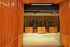 An indoor office corridor with modern industrial design featuring metal shipping container walls and orange accents.