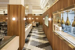 Modern restaurant interior featuring wood paneling on the walls and a checkered floor.
