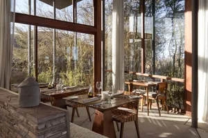 Modern restaurant interior featuring wooden furniture and glass windows.