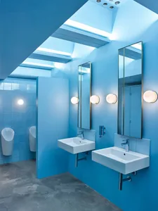 Modern restroom with blue tiled walls and concrete flooring.