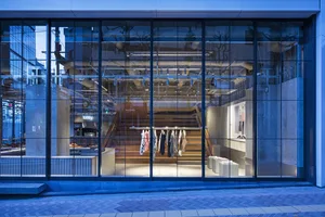 Modern retail storefront with large glass windows displaying clothing on racks.
