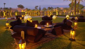 Outdoor seating arrangement with fabric cushions and lantern lighting near a jacuzzi pool at dusk.