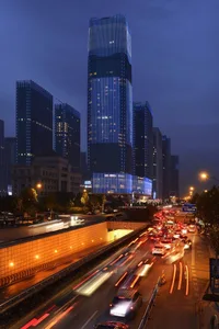 A bustling cityscape featuring modern glass skyscrapers and illuminated streets at night.