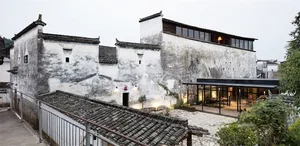 A white-washed traditional Chinese residence with a modern addition featuring concrete and glass.