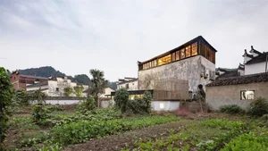 A modern, residential house with concrete walls and glass windows, situated in an urban setting.