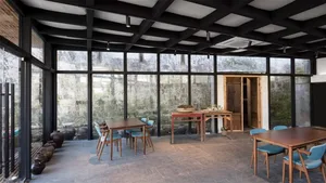 A spacious, industrial-themed restaurant with metal flooring and large glass windows.