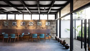 A modern coffee shop with a brick wall, glass windows, and wooden furniture.