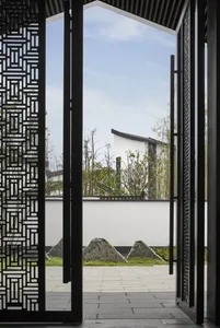 Modern garden featuring a glass wall with intricate patterns, set against a serene outdoor backdrop with greenery and stone a