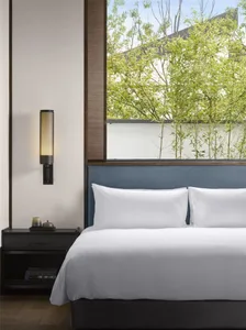 Modern minimalist bedroom featuring fabric walls, a white bed, and clean lines