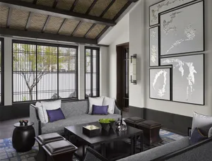 A modern living room with metal-frame windows, concrete furniture, and art on the walls.