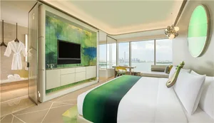 Modern hotel suite featuring a glass wall overlooking a cityscape.