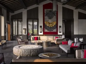 Modern interior design lobby with stone fireplace, fabric sofas, metal accents, and wooden flooring.